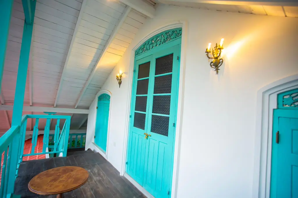 Upstairs balcony with turquoise doors and a small round table