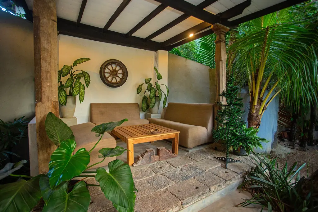 Open-air lounge with sofas, palms and a cartwheel on the wall