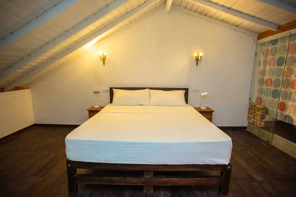 Attic bedroom under a white pitched ceiling with a double bed