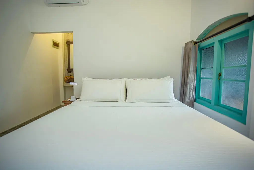 Cool white bedroom with a turquoise shuttered window