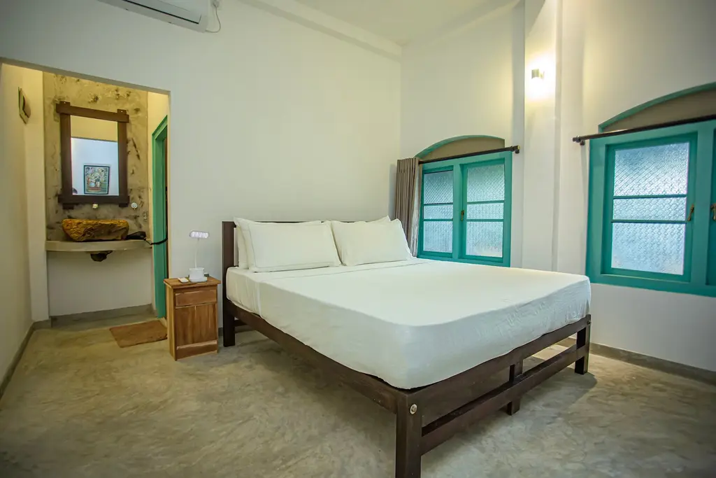 Double bedroom with a timber vanity mirror and turquoise windows