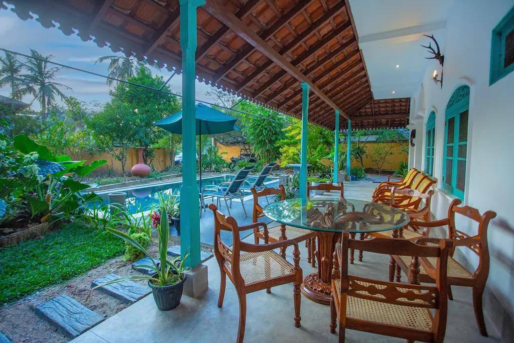 Dining table and timber chairs on the veranda, looking out to the pool
