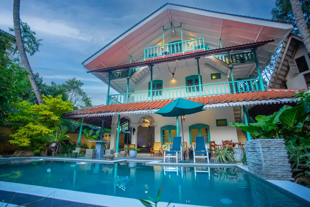 Front of Sekku House by day, with the pool, sun loungers and tropical garden